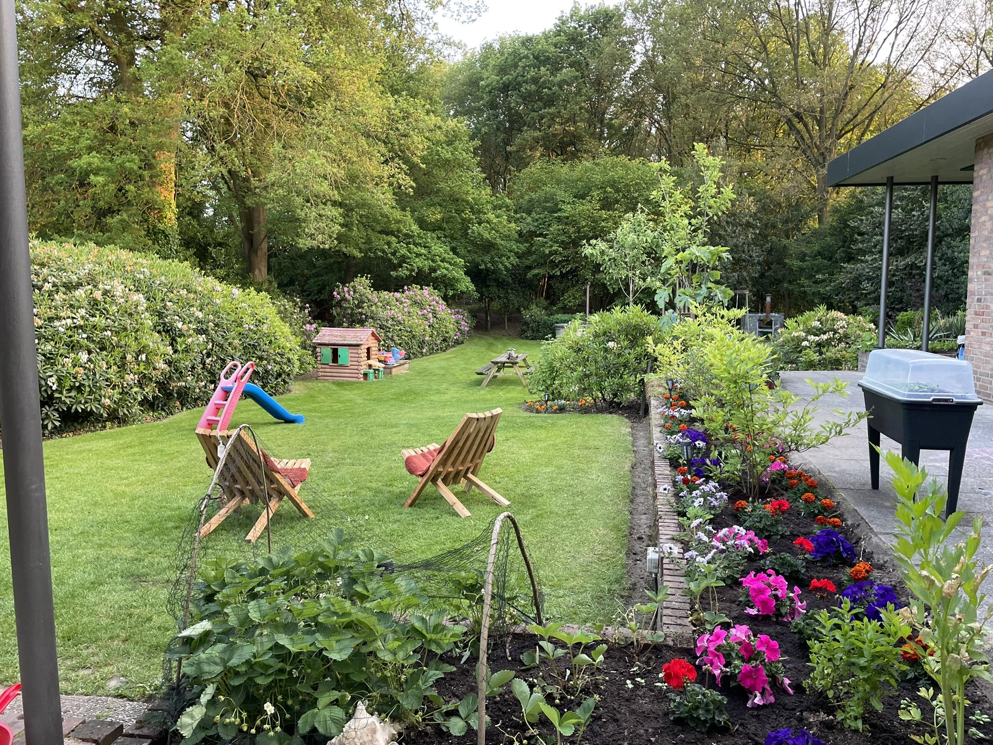 De tuin van Gastouderopvang May, met speeltoestellen en een moestuin